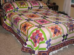 a bed with a quilt on top of it in a room next to a window