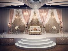 an elegant stage set up for a wedding ceremony with chandelier and couches