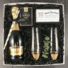 two champagne glasses and a bottle of wine in a gift box