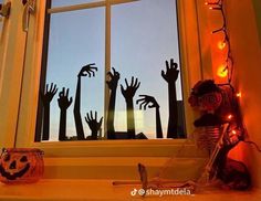 a window with halloween decorations in front of it and hands coming out from the windowsill