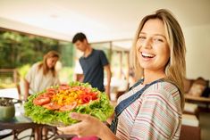 a woman holding a plate with vegetables on it in front of two men royalty - foto