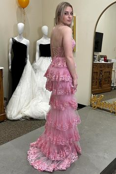 a woman in a pink dress standing next to mannequins