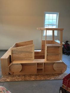 a wooden toy train set sitting on top of a floor next to a window in a room