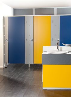 a bathroom with yellow, blue and grey cabinets