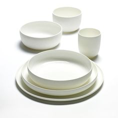 a white table setting with four plates and two cups on the top one is empty