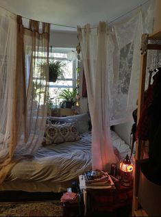 an unmade bed with sheer curtains hanging from it's sides in a bedroom