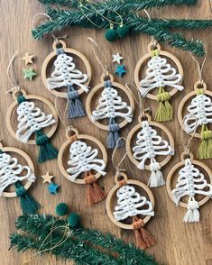 christmas tree ornaments made from yarn and wooden hoops on a table with pine branches