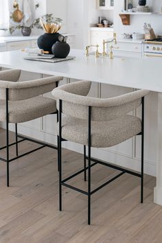 three chairs sitting on top of a white counter in a kitchen next to an island