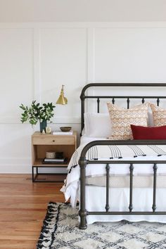 a bed sitting on top of a wooden floor next to a white wall