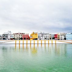 the water is green and blue with buildings in the background on a cloudy day,