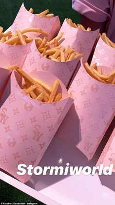 pink paper bags filled with french fries on top of a table