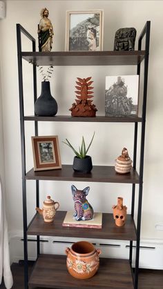 a shelf with vases and pictures on it