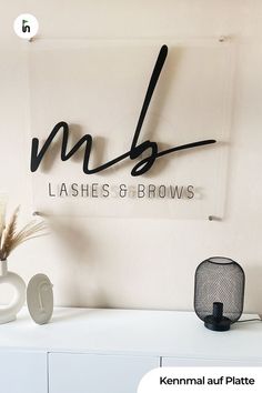 the logo for lashes and brows is displayed above a white dresser with a vase on it