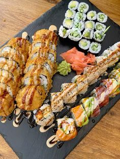 an assortment of sushi on a black platter