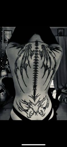 the back of a woman's body with tattoos on it and an image of a dragon