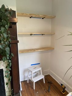 a white chair sitting on top of a hard wood floor next to a wooden shelf