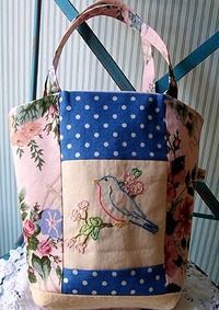 two purses sitting on top of a table with flowers and polka dot fabric around them