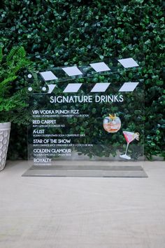 a glass plaque with the words signature drinks on it next to a potted plant