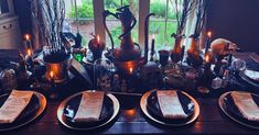 the table is set with silverware, candles and menus in front of an open window