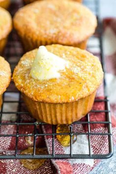 several muffins cooling on a wire rack with butter and some other toppings