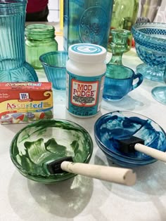 the table is covered with blue and green glass dishes, including one for making soap