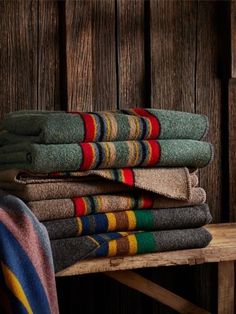 a stack of folded towels sitting on top of a wooden table next to a wall