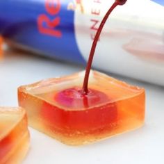 a can of soda being poured onto small pieces of fruit jellies on a white surface