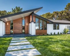 a modern house with grass and trees in the background