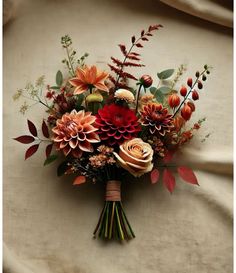 a bouquet of flowers sitting on top of a white cloth covered table next to a wall