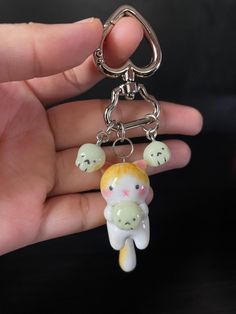 a hand holding a keychain with a small cat on it's back