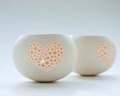 two white vases with holes in the middle one has a heart painted on it