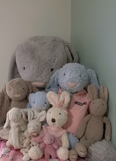 a pile of stuffed animals sitting next to each other on top of a pink blanket