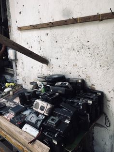 a table full of old cameras sitting on top of a wooden pallet next to a white wall