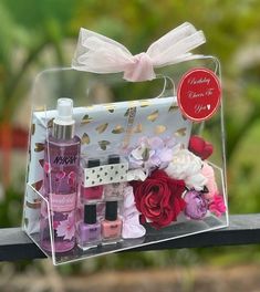 a clear box with pink and red flowers in it on a wooden table next to a bottle of perfume