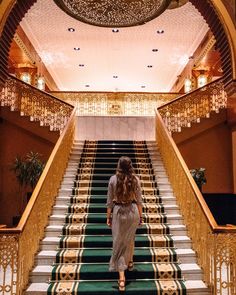 a woman is walking down the stairs in an ornate building