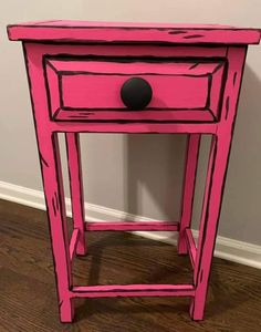 a pink wooden table with a black ball on it's top and bottom drawer