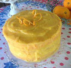 a yellow cake sitting on top of a table covered in frosting and oranges