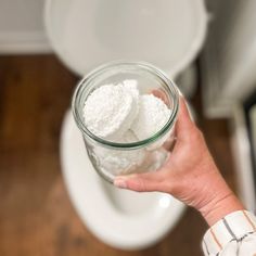 a person holding a glass jar filled with white powder