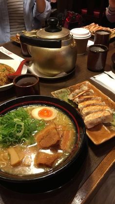 a wooden table topped with bowls filled with soup and meat covered in broccoli