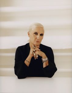 a woman sitting at a table with her hands on her chin