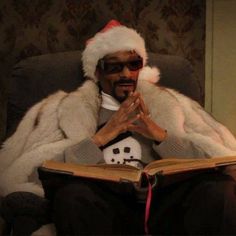 a man sitting in a chair wearing a santa hat and reading a book