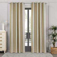 a living room with a white rug and beige curtains hanging on the windowsills