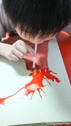 a young boy is painting with red paint