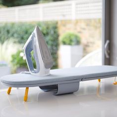 an ironing board sitting on top of a white table next to a window sill