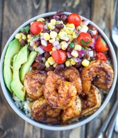 a bowl filled with shrimp, beans and corn on top of rice next to a fork