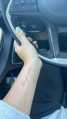 a woman driving a car with her hand on the steering wheel and writing on it