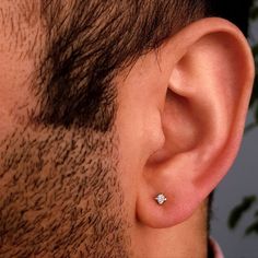 a close up of a man's ear with a single diamond in it