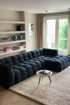 a large blue couch sitting on top of a rug in a living room next to a window