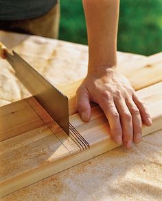 a person holding a knife on top of a wooden board