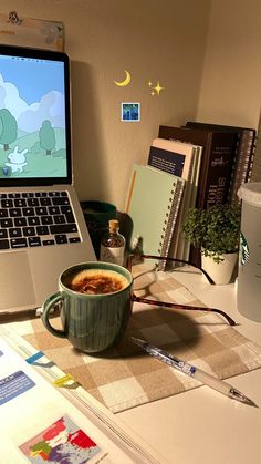 an open laptop computer sitting on top of a desk next to a cup of coffee